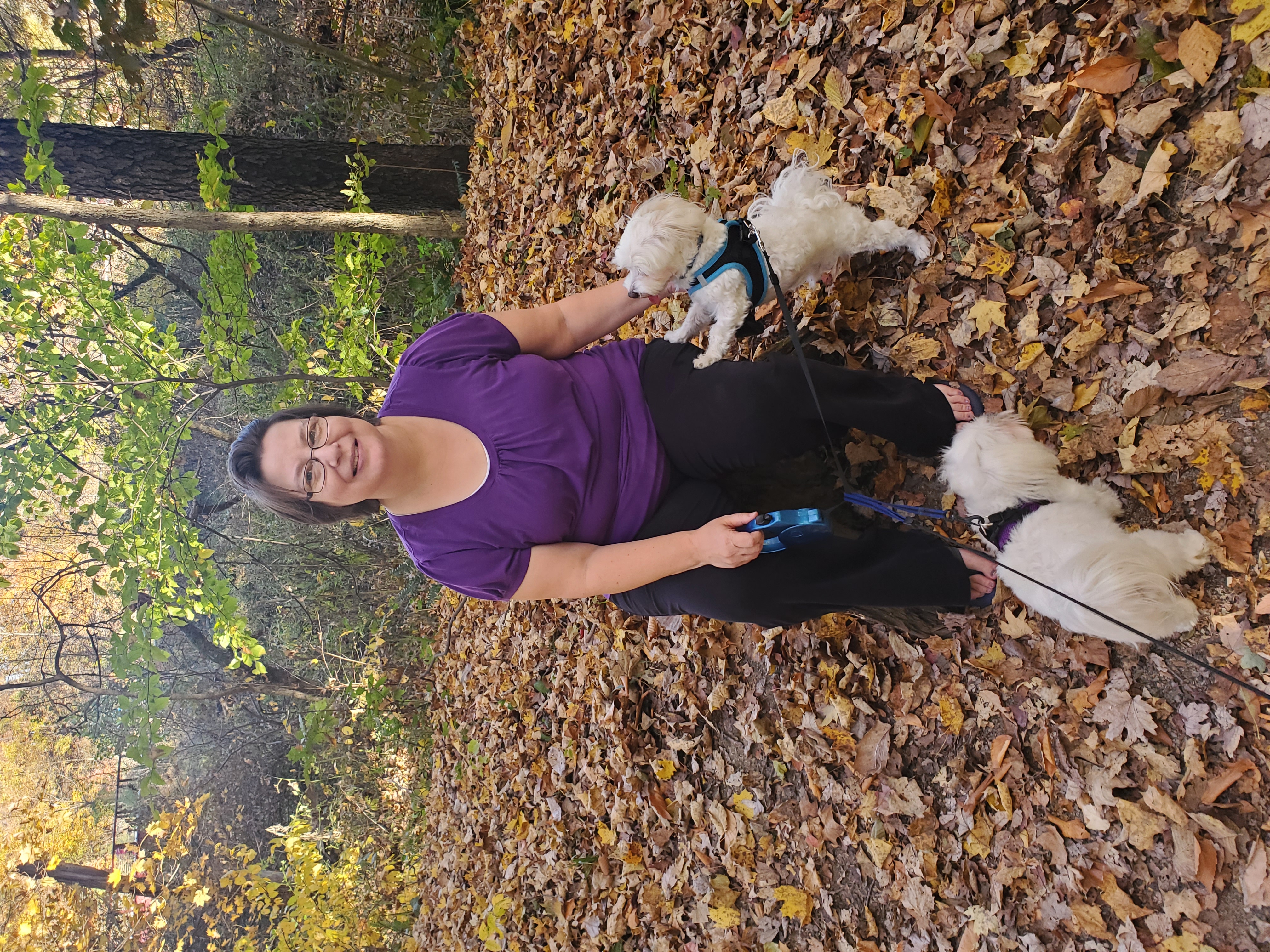 Sharon Miller smiling in the woods with her two dogs